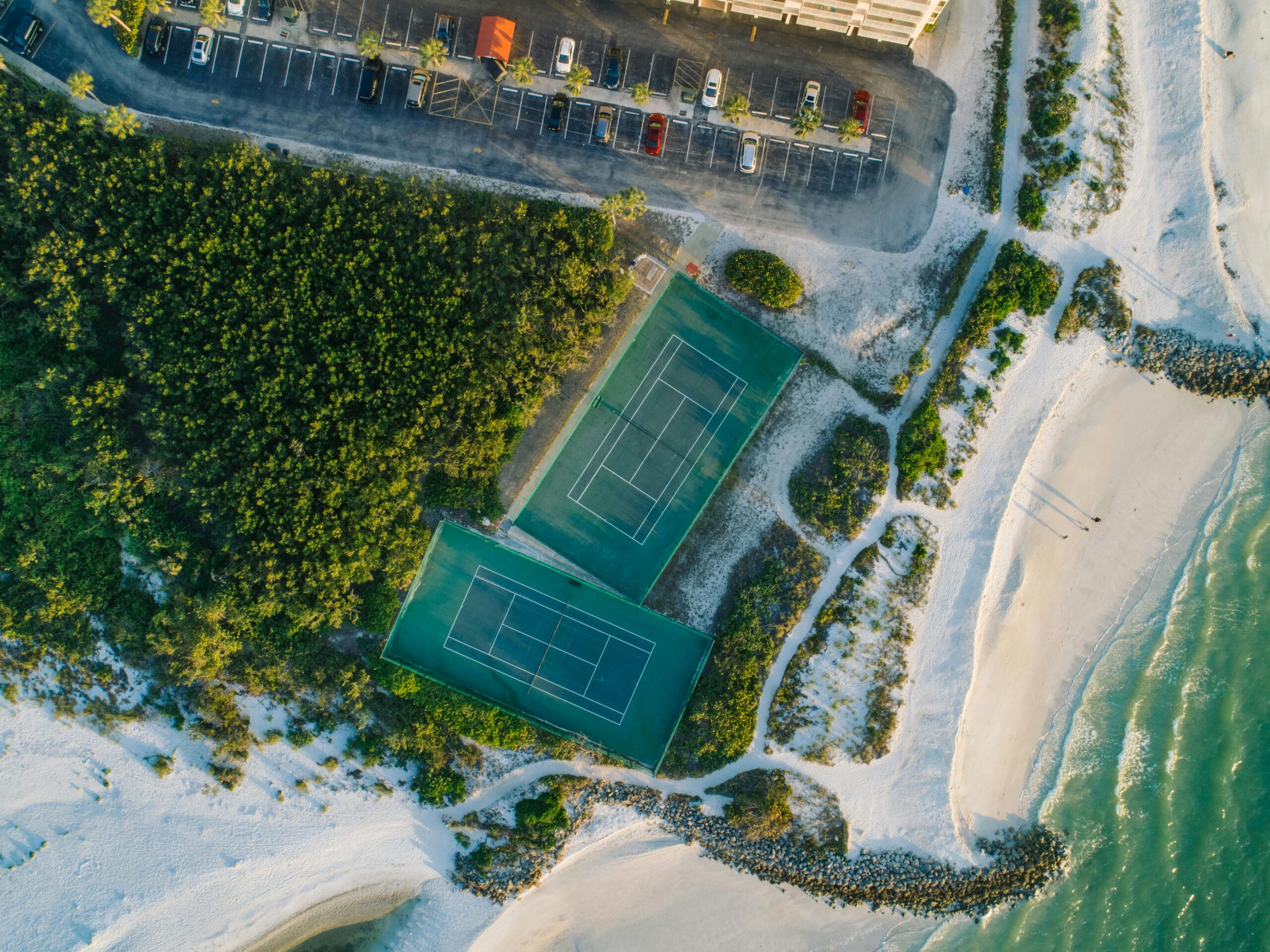 Vista aerea di un resort con campi da tennis sul mare